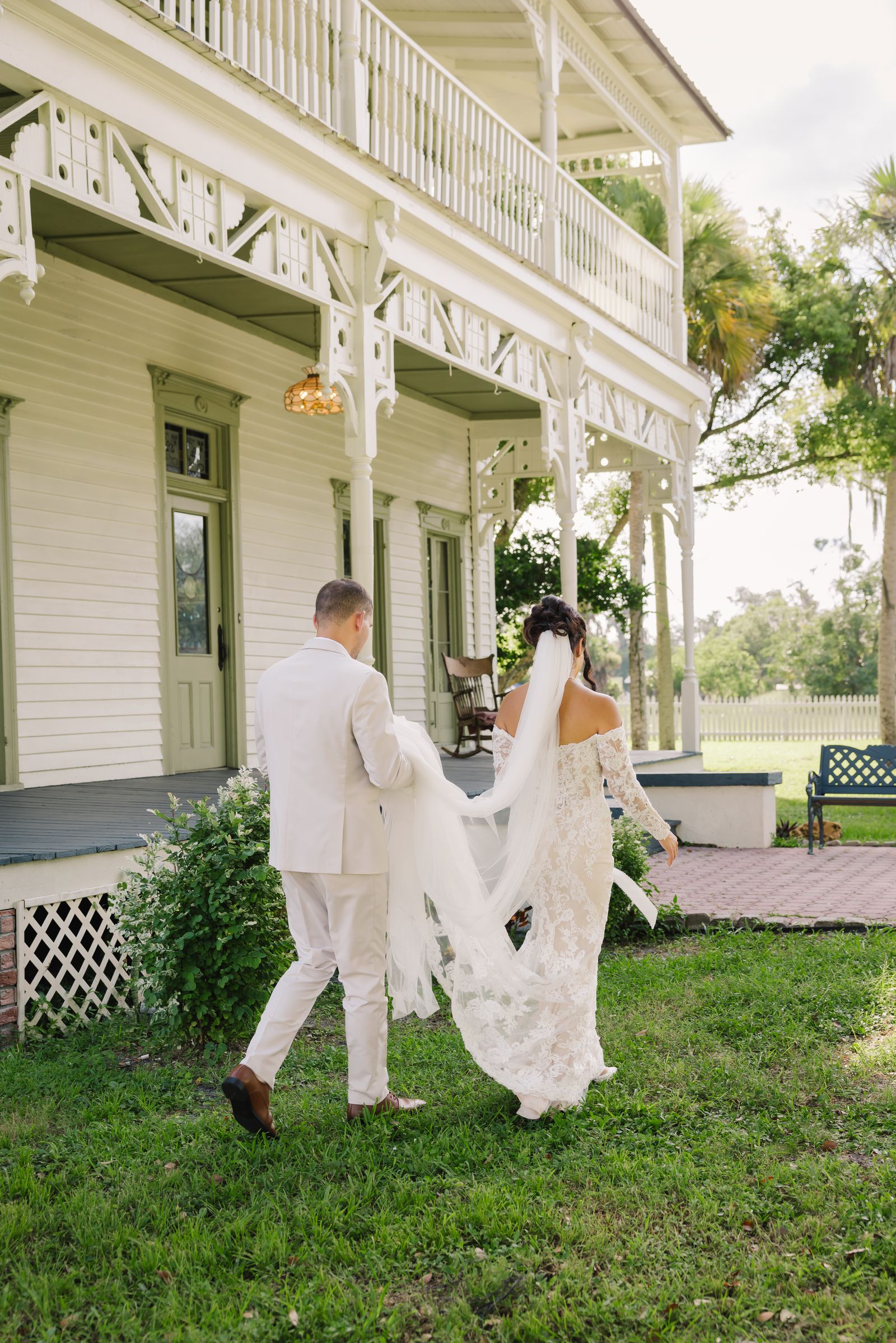 A couple walking past the veranda, her train trailing behind